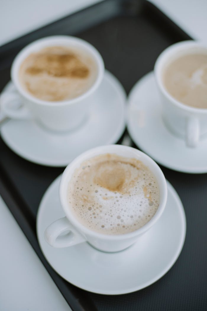 Three cappuccino cups with foam art arranged on saucers, perfect for coffee lovers.