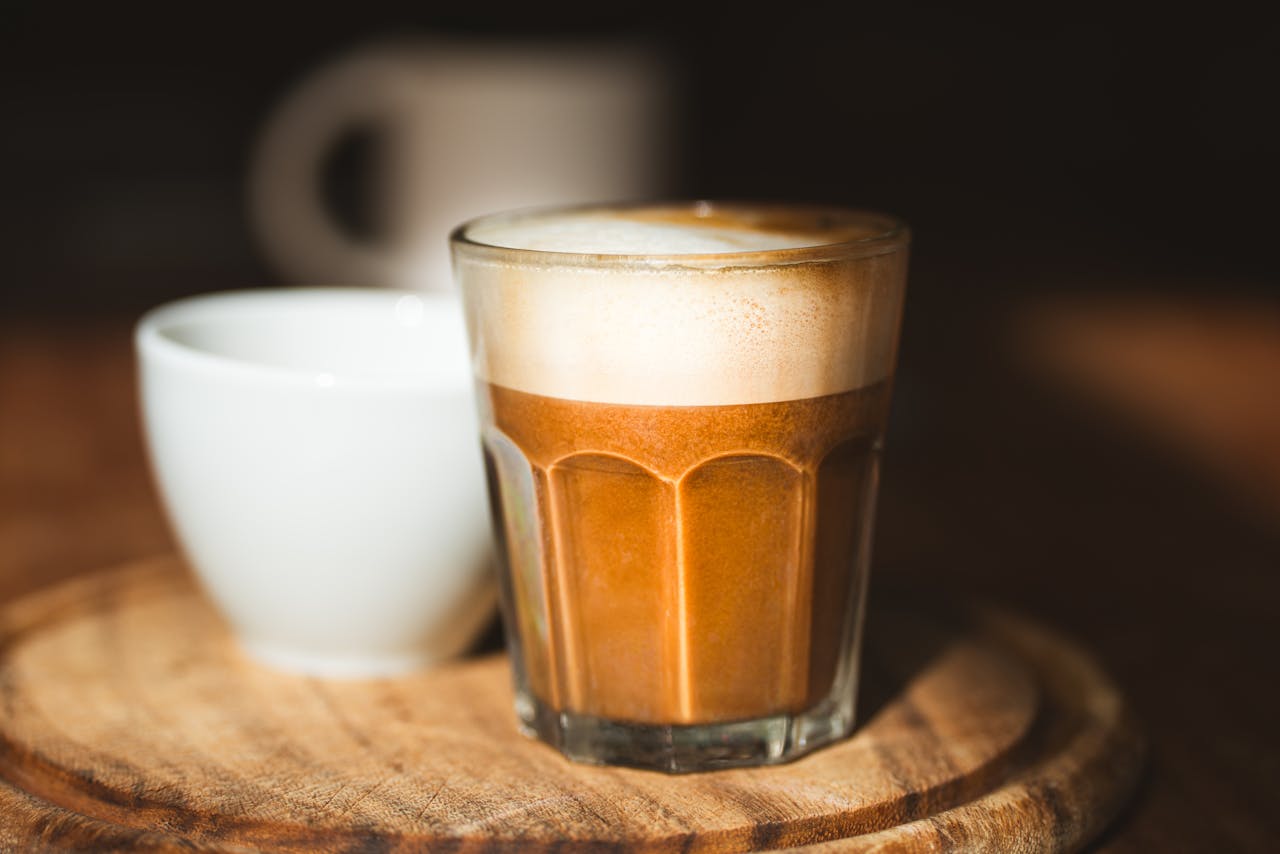 Close-up of a frothy cappuccino served on a wooden table in a cozy cafe setting.